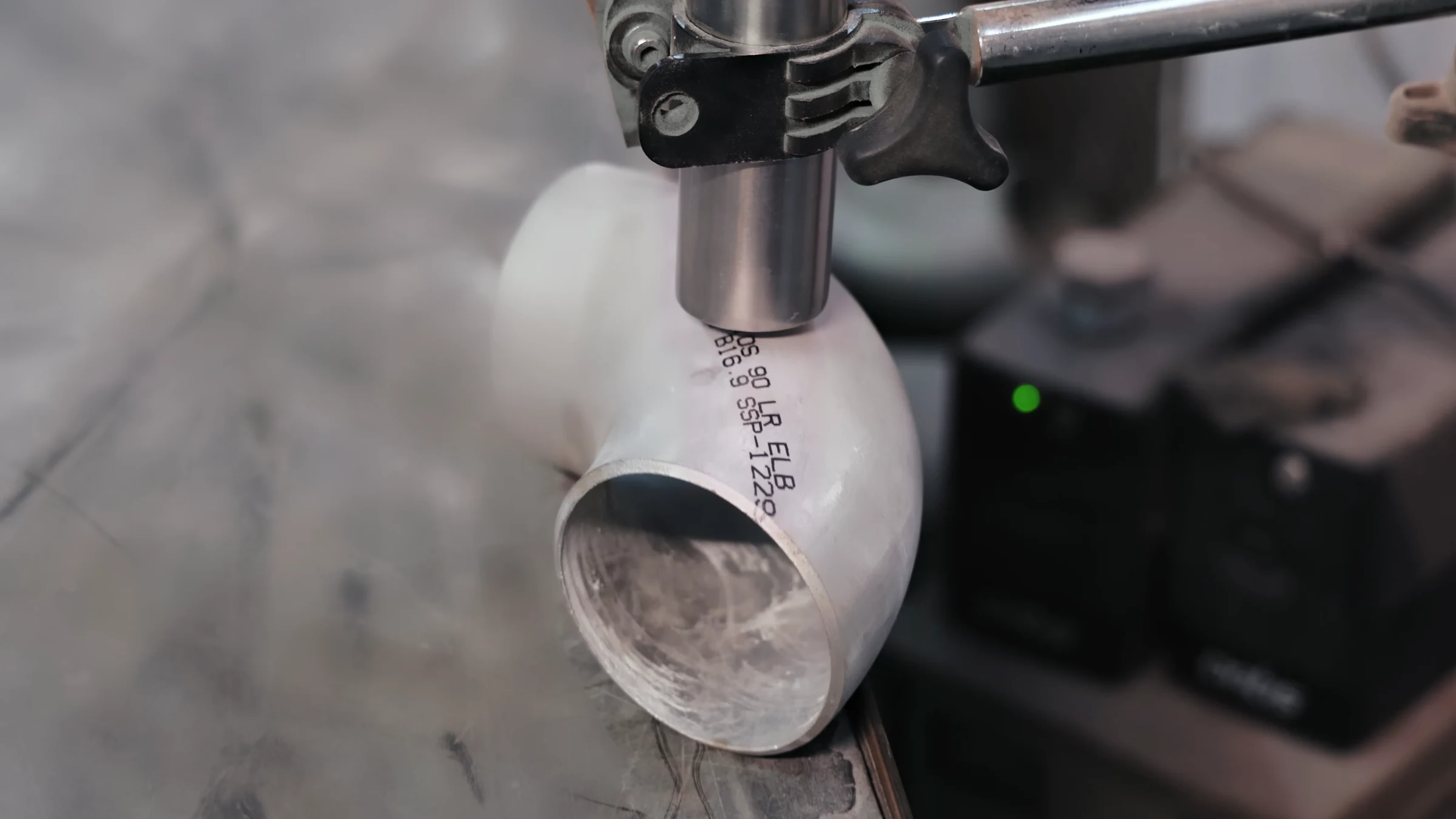 Marking head over a stainless-steel 90° long-radius elbow carrying its B16.9 marking